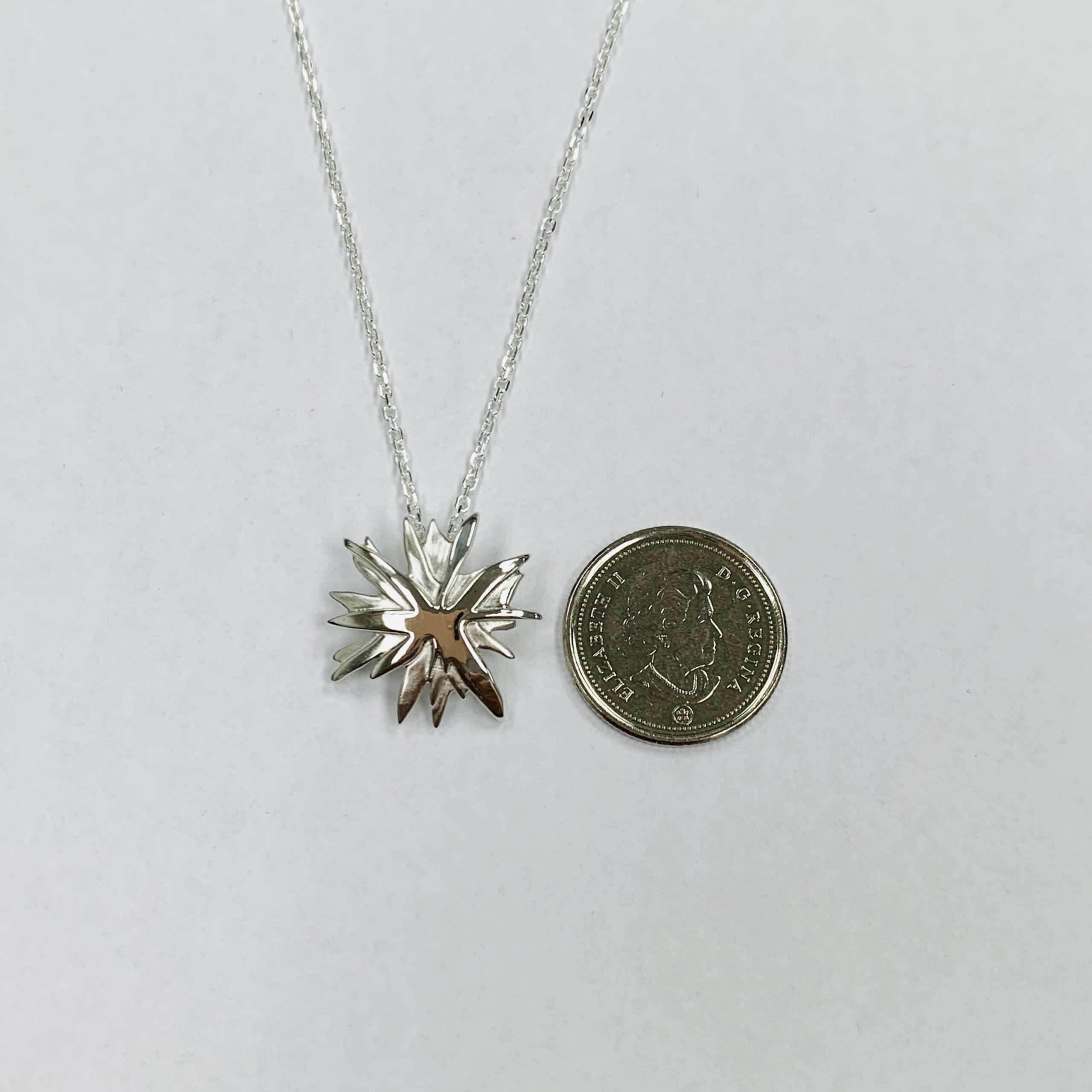 Mining Matters ‘The Spark’ Pendant shown side by side with a Canadian dime for size reference